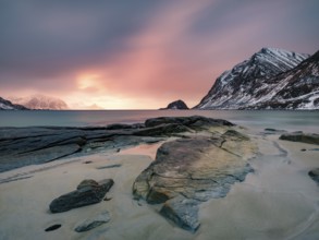 Rocks on Haukland beach in the evening light, snow-capped mountains in the background, Vestvågøya,