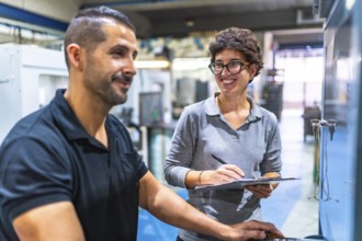 Male manual worker talking with female manager while using computer in the factory