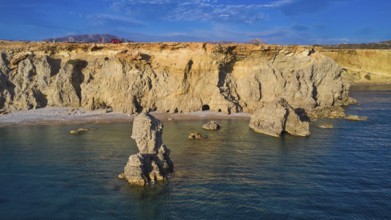 Impressive coastal landscape with imposing rock formations under a clear sky, drone shot, evening