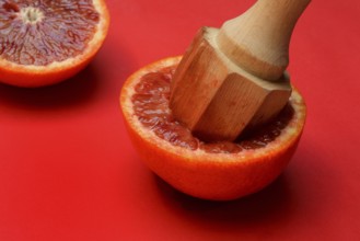 Halved blood orange with citrus squeezer, orange