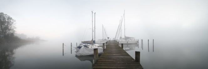 Quiet autumn morning on Lake Chiemsee, jetty with sailing boats in dense fog, Prien am Chiemsee,