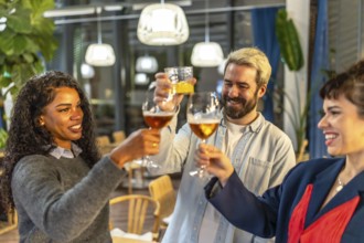 Multi-ethnic friends raising glasses and toasting celebrating success at night party in a bar