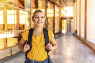 Portrait of a blonde happy female student standing at the university