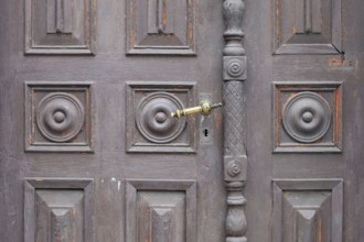 Old antique wooden door with decorative round patterns and a metal door handle, St. Martin,