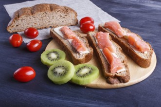 Smoked salmon sandwiches with butter on dark wooden background. cherry tomatoes. close up