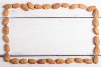 Rectangular frame made from almonds on white wooden background, flat lay. top view