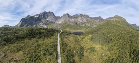 Panoramic aerial view of road in mountain scenery, passing lakes and meadows, road from E10 to