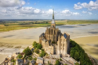 Aerial view of the abbey on a hill, surrounded by sandy areas and a wide landscape, Le