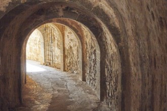 An old, dark tunnel with stone walls and a glow of light at the end, Venetian Sea Fortress, Leper