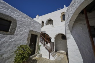 Courtyard of a historic building with white walls and a wooden staircase, Inside the monastery,