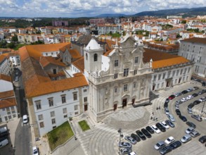Historic baroque church in the city with a square in front of it and parked cars, aerial view,