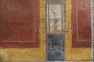 Close-up of reddish brown, blue and white frescoes on yellow wall of old residential building at