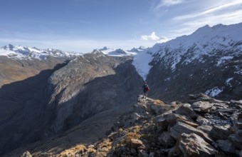 Mountaineer standing on a rock, surrounded by an impressive mountain landscape with snow-covered