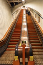 Passers-by on a wooden escalator in the Sint-Annatunnel, heritage-protected St Anne's Tunnel under