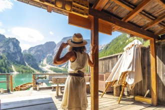 Woman wearing straw hat enjoying stunning panorama of lake braies, also known as pragser wildsee,