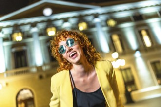 Sensual modern woman in sunglasses dancing along the city at night