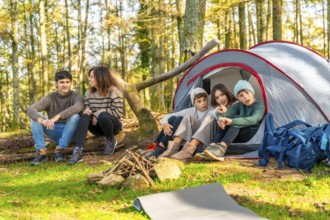 Caucasian family with three children enjoying day camping in the forest