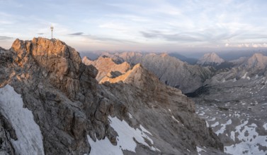 Summit of the Zugspitze with golden summit cross, alpenglow at sunset, Northern Limestone Alps,