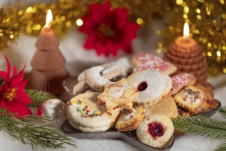 Festively decorated plate with biscuits, surrounded by candles and poinsettias