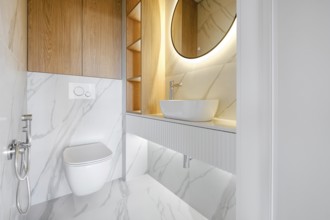 This contemporary bathroom showcases minimalistic design with marble walls and a circular mirror,