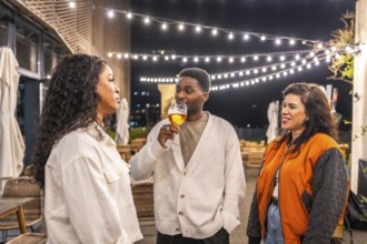 Multi-ethnic happy friends talking while enjoying drinking beer at roof of a bar