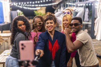 Multi-ethnic friends taking selfie while celebrating a party in an outdoors terrace of a bar