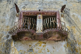 An abandoned balcony with rusty railings and damaged façade on an old building, Italian Governor's