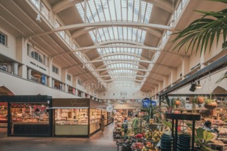 A bright, airy market hall with various stalls selling fresh fruit and vegetables under a high