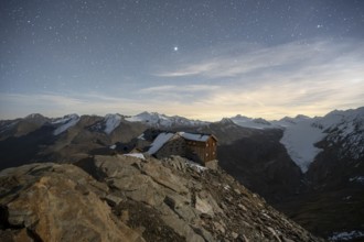 Mountain landscape under a starry sky, night shot, mountain hut Ramolhaus in autumn with snow, view