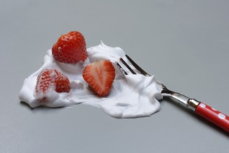Strawberries on a fork with whipped cream