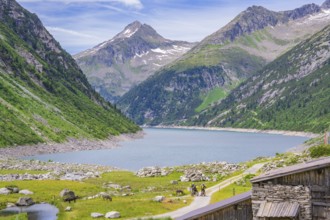 Scenery of mountains with a lake and two cyclists on a path, green nature and blue sky, Klein