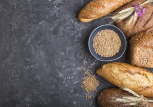 Different kinds of fresh baked bread on a black concrete background. top view, flat lay, copy space