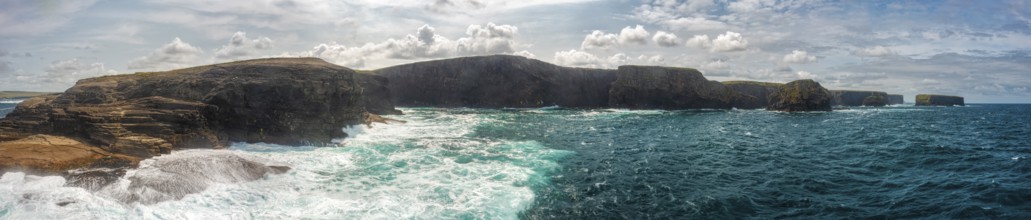 Vast coastal landscape with dramatic cliffs and cloudy skies over the deep blue sea, Kilkee