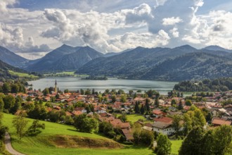 Picturesque lakeside village in the Alps, surrounded by green meadows and mountains under a cloudy