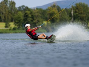 Boy or girl, summer holiday with wakeboard, water splashes, red life jacket, water skiing and