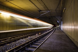 A train travels at high speed through an illuminated tunnel