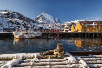 Fishing village with yellow and red houses in front of snow-covered mountains, Nusfjord,