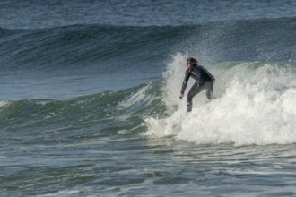 Surfer riding a wave on an Atlantic Ocean beach. Camaret, Crozon, Brittany, France, Europe