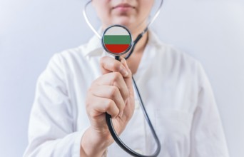 Female doctor holding stethoscope with Bulgaria flag. National health system of Bulgaria