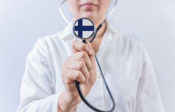 Female doctor holding stethoscope with Finland flag. National Health System of Finland
