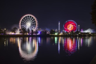 Atmospheric funfair at night with brightly lit Ferris wheel and colourful lights reflected in the