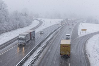 Motorway in snowfall with several trucks and cars on the road, Winnenden, Baden-Württemberg,