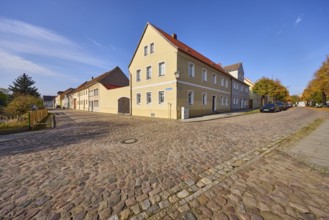 Residential building, cobblestone pavement, blue sky with cirrostratus clouds, intersection of