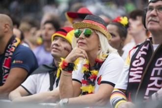 A woman watches the football match in the fan zone at the Brandenburg Tor during the quarter-final