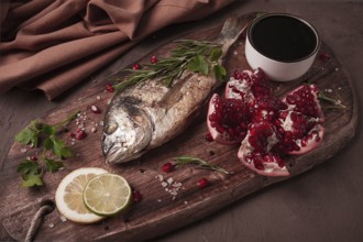 Fried dorado fish, with spices and herbs, on a wooden board, pomegranate sauce, close-up, no people