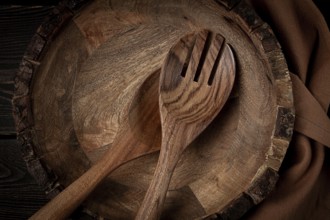 Wooden plate, handmade, with salad spoons, top view, on a wooden table, no people