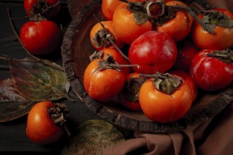Fresh persimmon, in a wooden plate, top view, no people