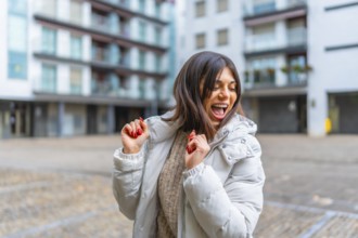 Happy and ecstatic woman wearing winter clothes dancing alone in the city