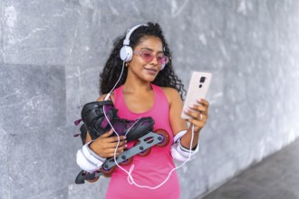 Latin beauty woman with inline skates listening to music with mobile phone and headphones at urban
