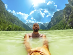 Tourist swimming in the crystal clear waters of lago di landro, surrounded by the breathtaking